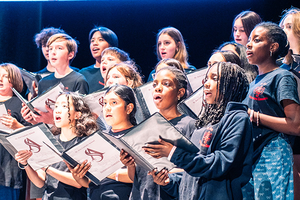 Young performers singing in a choir on stage