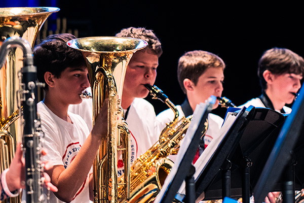 Young performers playing various horn instruments on stage